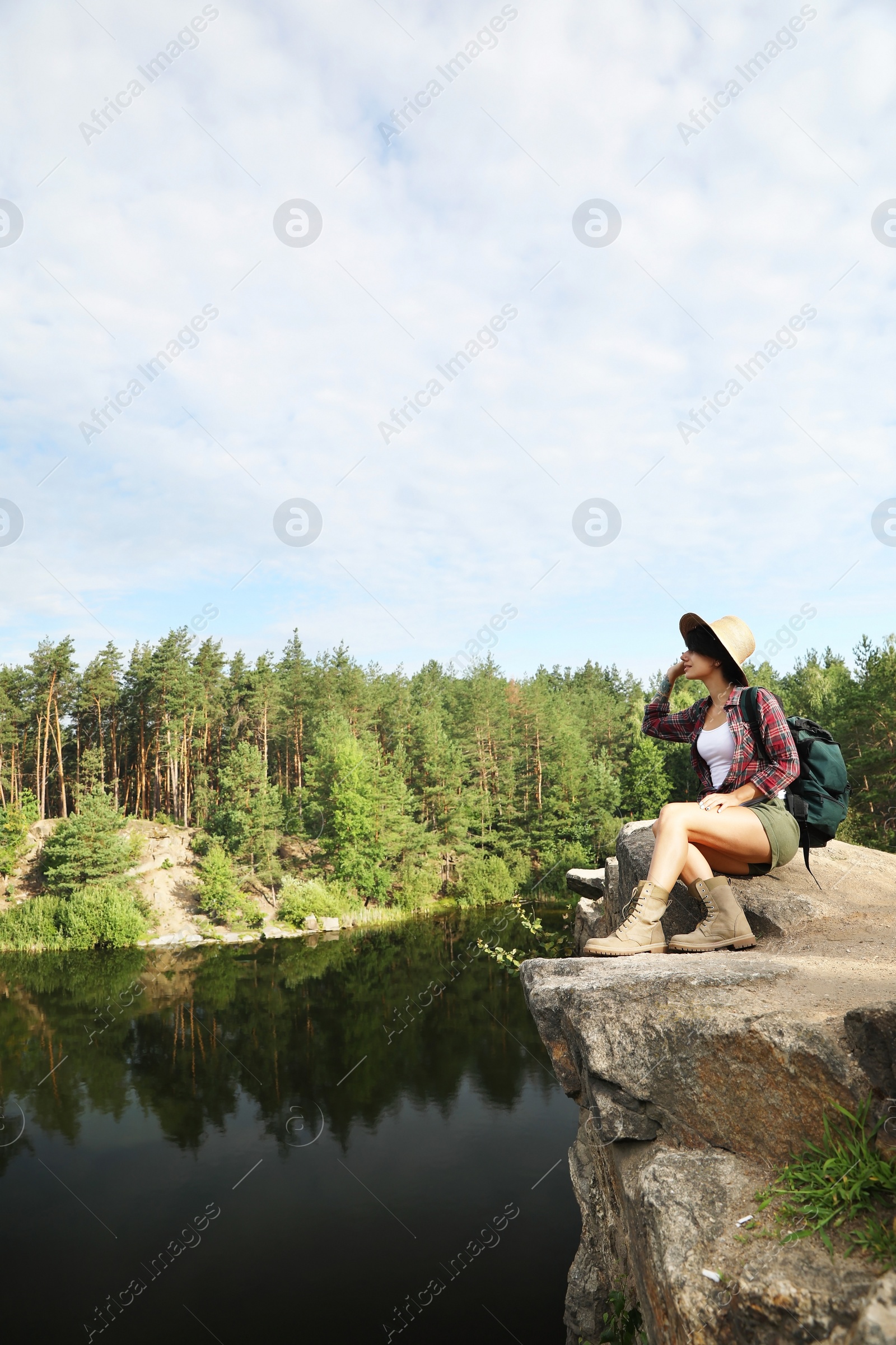 Photo of Young woman on rock near lake and forest. Camping season