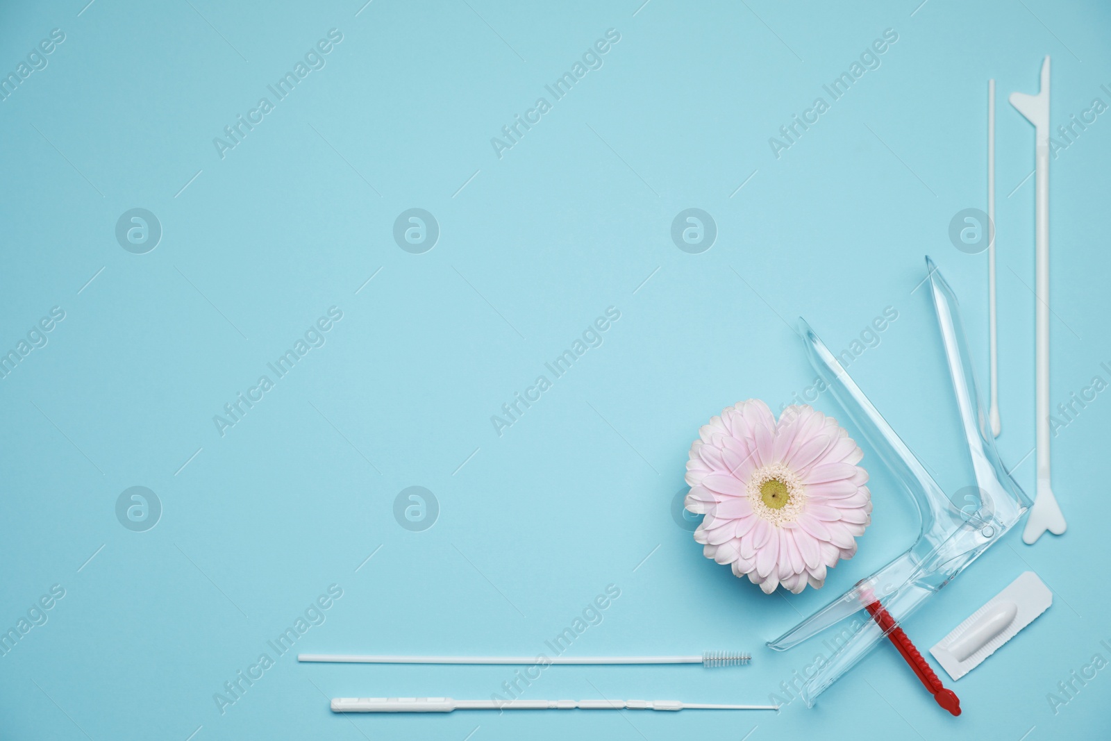 Photo of Sterile gynecological examination kit and gerbera flower on light blue background, flat lay. Space for text