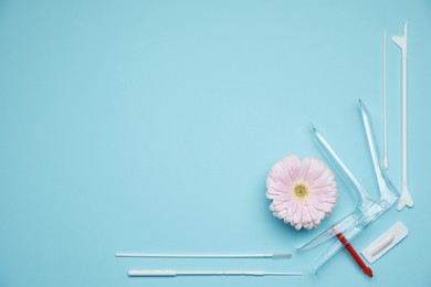Photo of Sterile gynecological examination kit and gerbera flower on light blue background, flat lay. Space for text