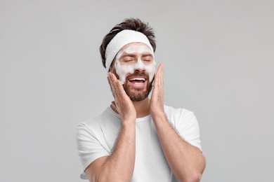 Photo of Man with headband washing his face on light grey background