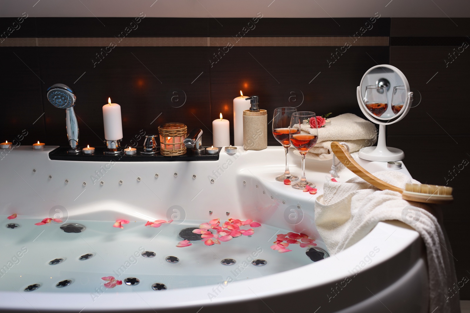 Photo of Bathtub with glasses of wine and candles indoors. Romantic atmosphere