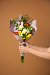 Photo of Woman with beautiful bouquet of freesia flowers on color background