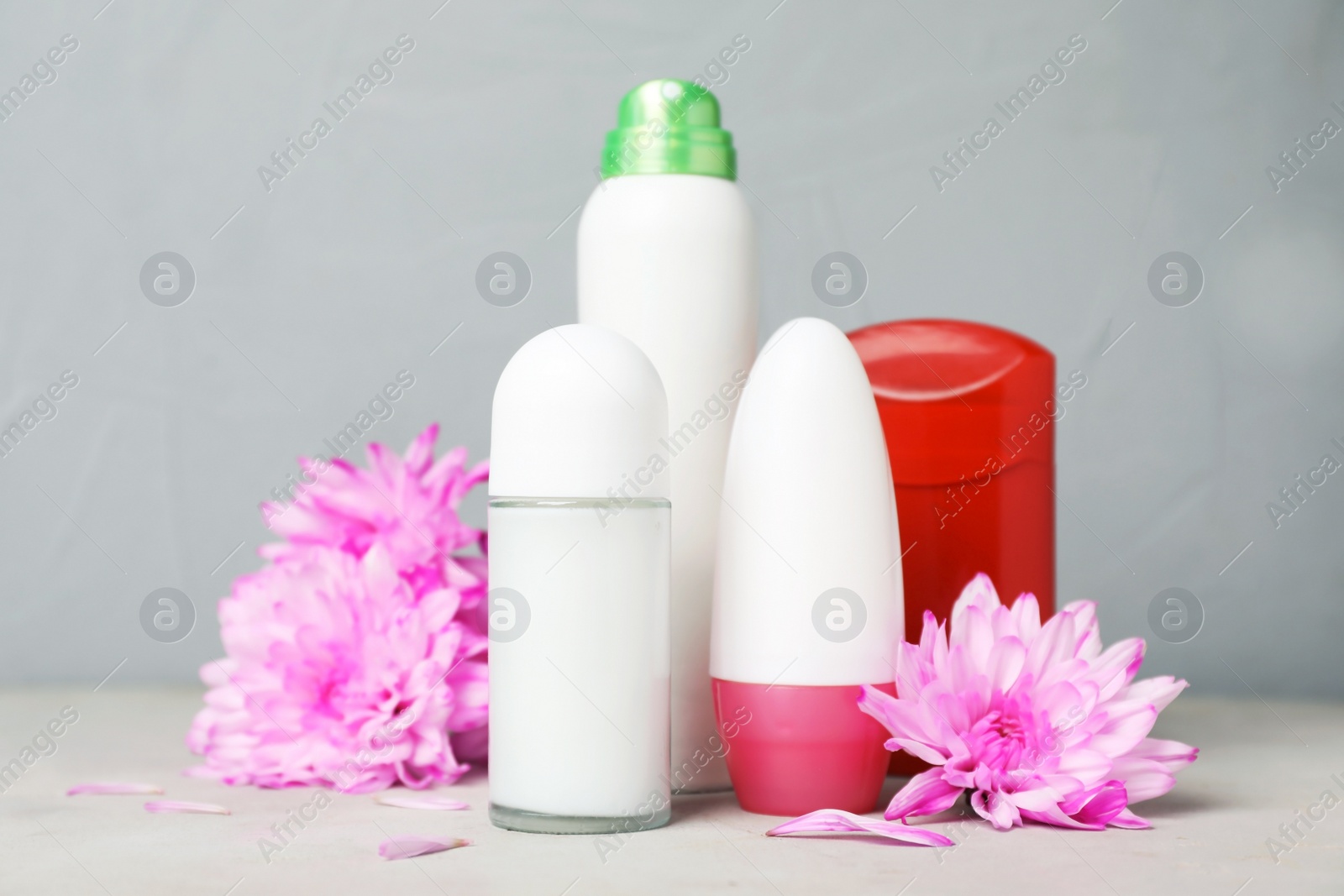 Photo of Different deodorants and flowers on table. Personal hygiene