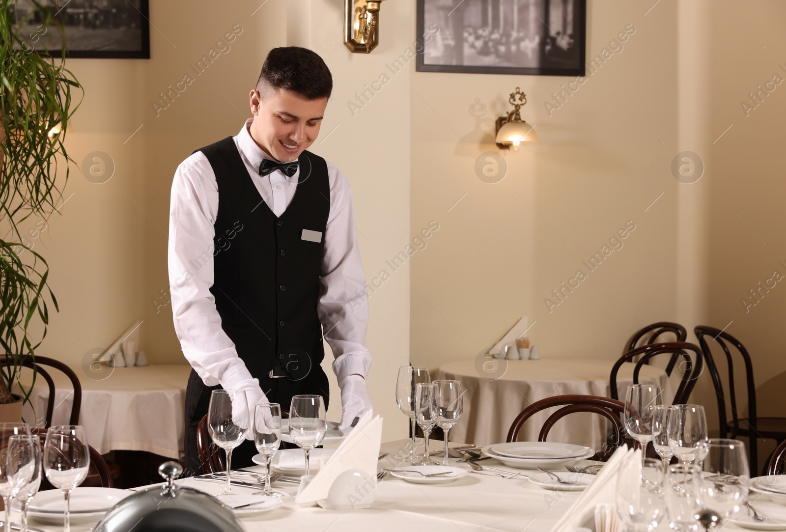 Photo of Man setting table in restaurant. Professional butler courses