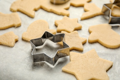 Photo of Raw Christmas cookies and cutters on baking parchment