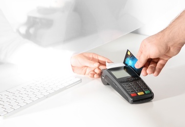 Photo of Man using bank terminal for credit card payment at cash department window, closeup