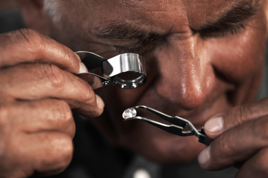 Photo of Professional jeweler evaluating beautiful gemstone, closeup view