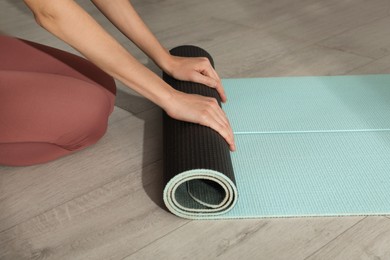 Photo of Woman rolling yoga mat on floor, closeup