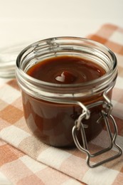 Photo of Tasty barbecue sauce in glass jar on table, closeup