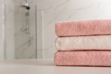 Stack of clean towels on table in bathroom, closeup. Space for text