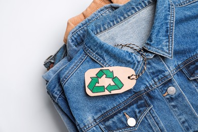 Photo of Stack of clothes with recycling label on white background, closeup