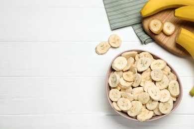 Photo of Freeze dried and fresh bananas on white wooden table, flat lay. Space for text
