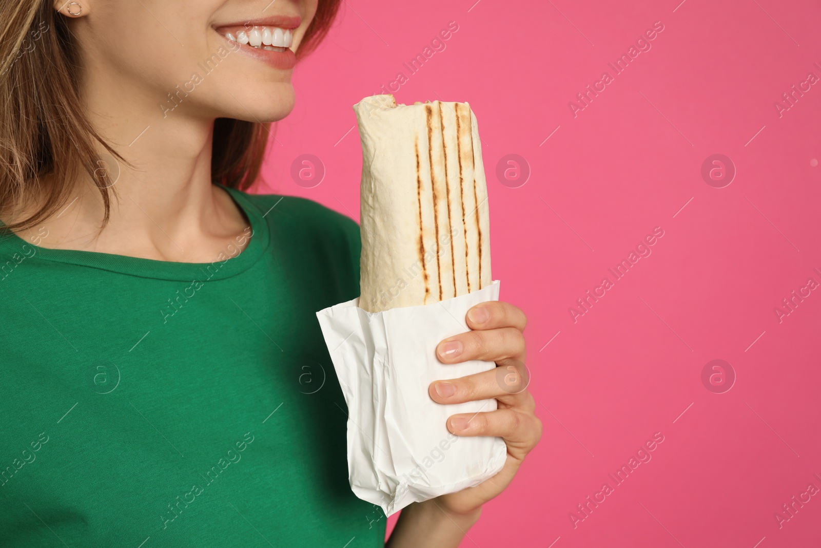 Photo of Young woman with delicious shawarma on pink background, closeup. Space for text