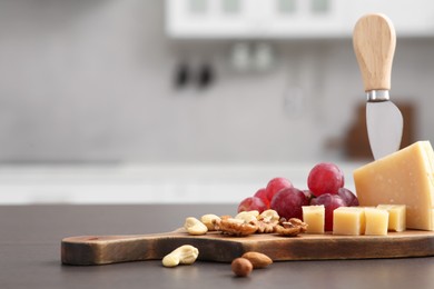 Wooden bord with cut cheese and, nuts and grape on countertop in kitchen, space for text