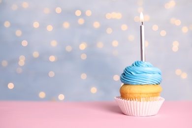 Birthday cupcake with candle on table against festive lights, space for text