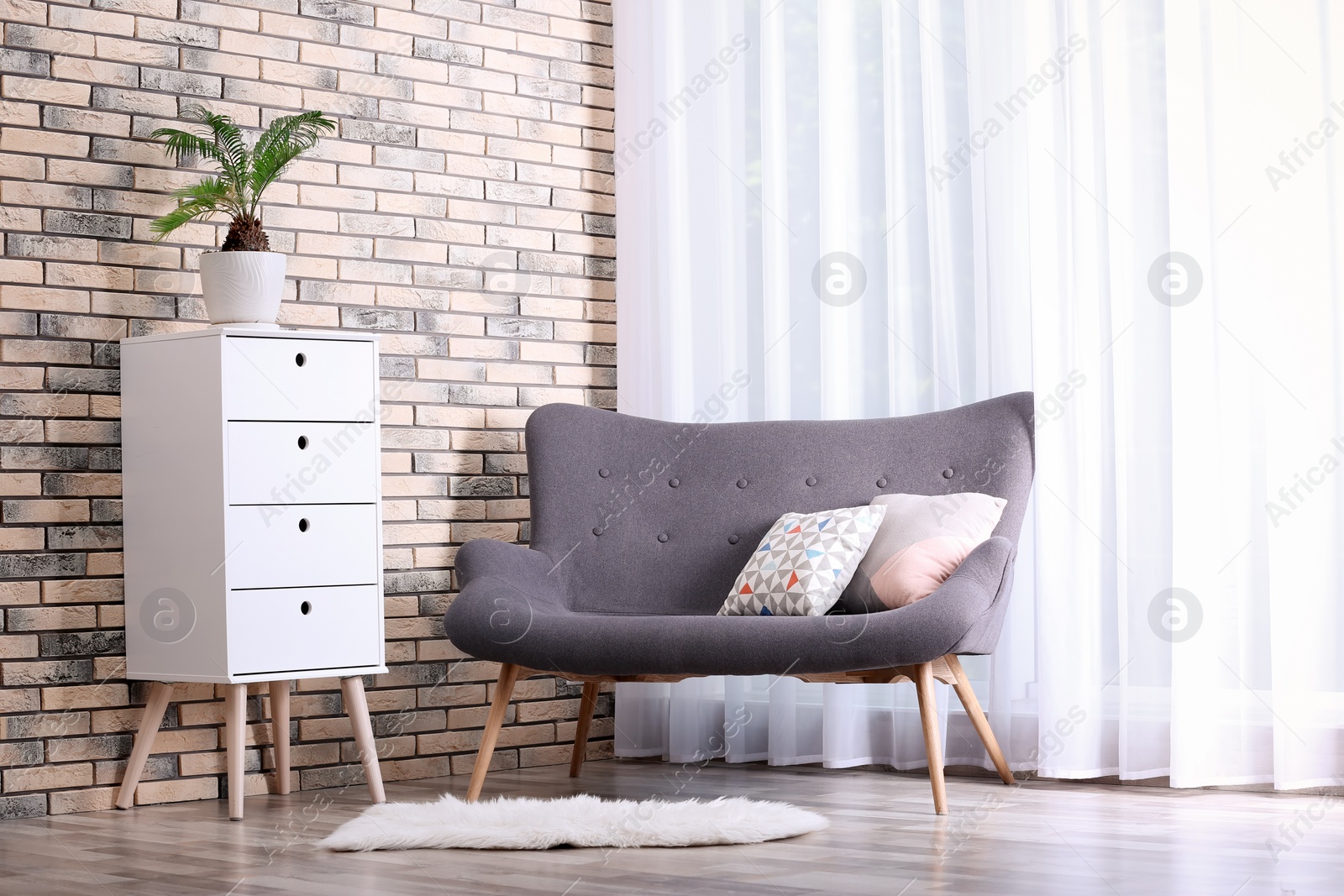 Photo of Stylish living room interior with chest of drawers and sofa