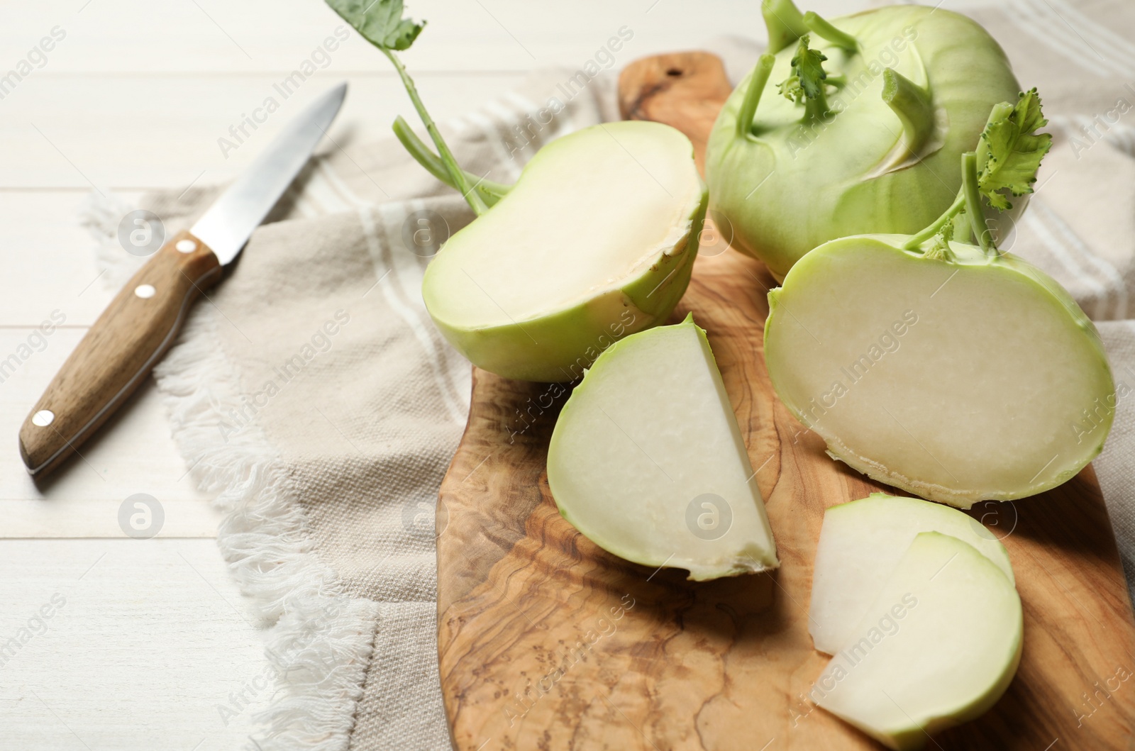 Photo of Whole and cut kohlrabi plants on white wooden table