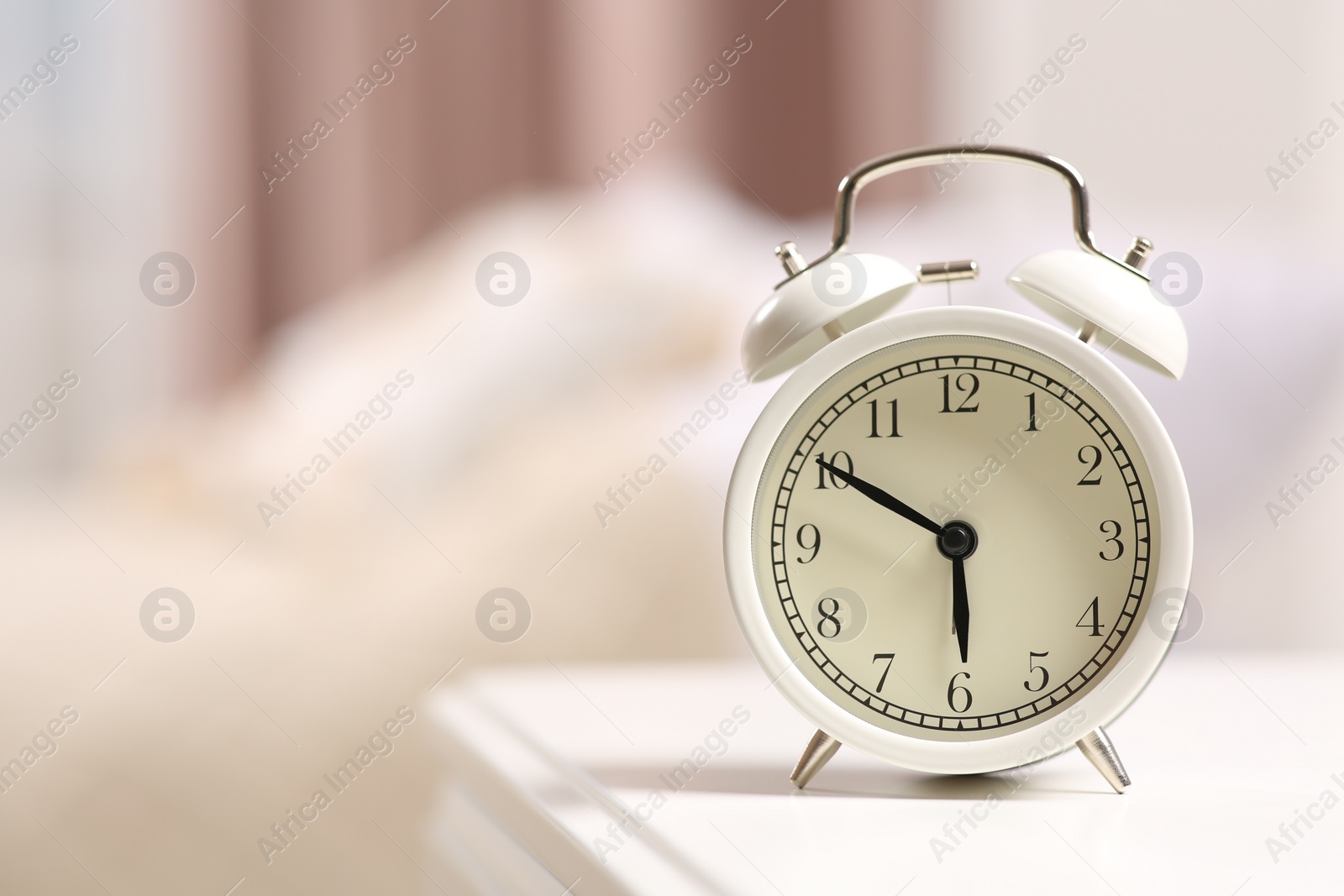 Photo of Stylish alarm clock on white nightstand indoors. Space for text