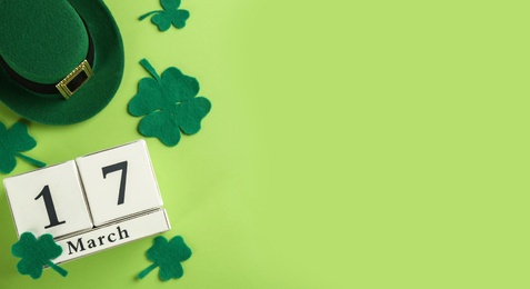 Photo of Leprechaun's hat, block calendar and St. Patrick's day decor on green background, flat lay. Space for text