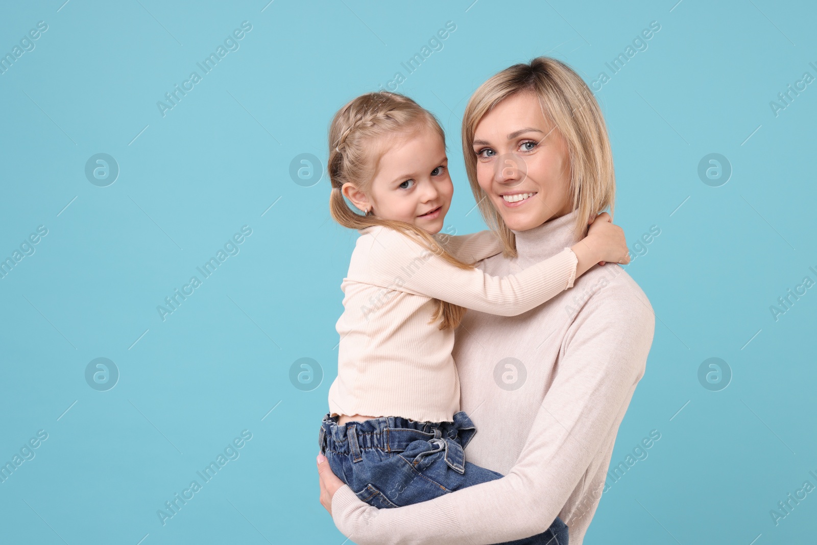 Photo of Daughter hugging her happy mother on light blue background. Space for text