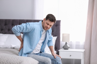 Young man suffering from back pain at home