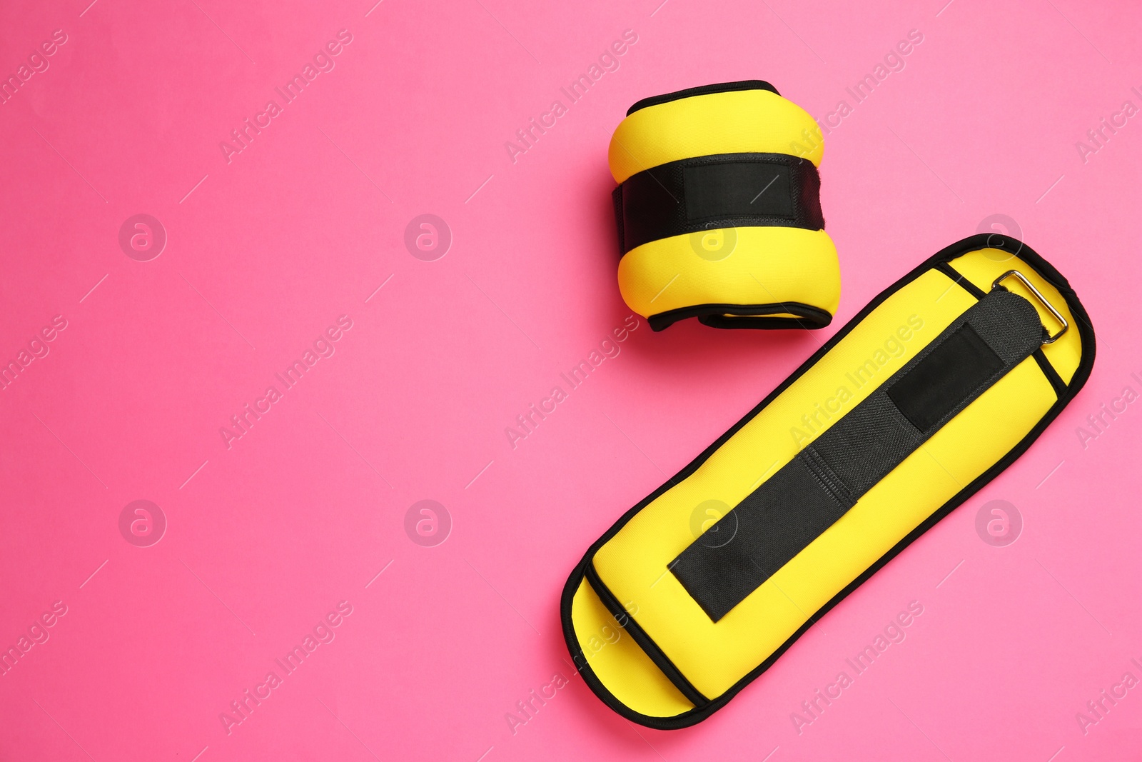 Photo of Yellow weighting agents on pink background, flat lay. Space for text