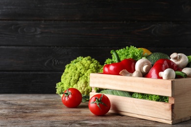 Photo of Wooden crate full of fresh ripe vegetables on table. Space for text