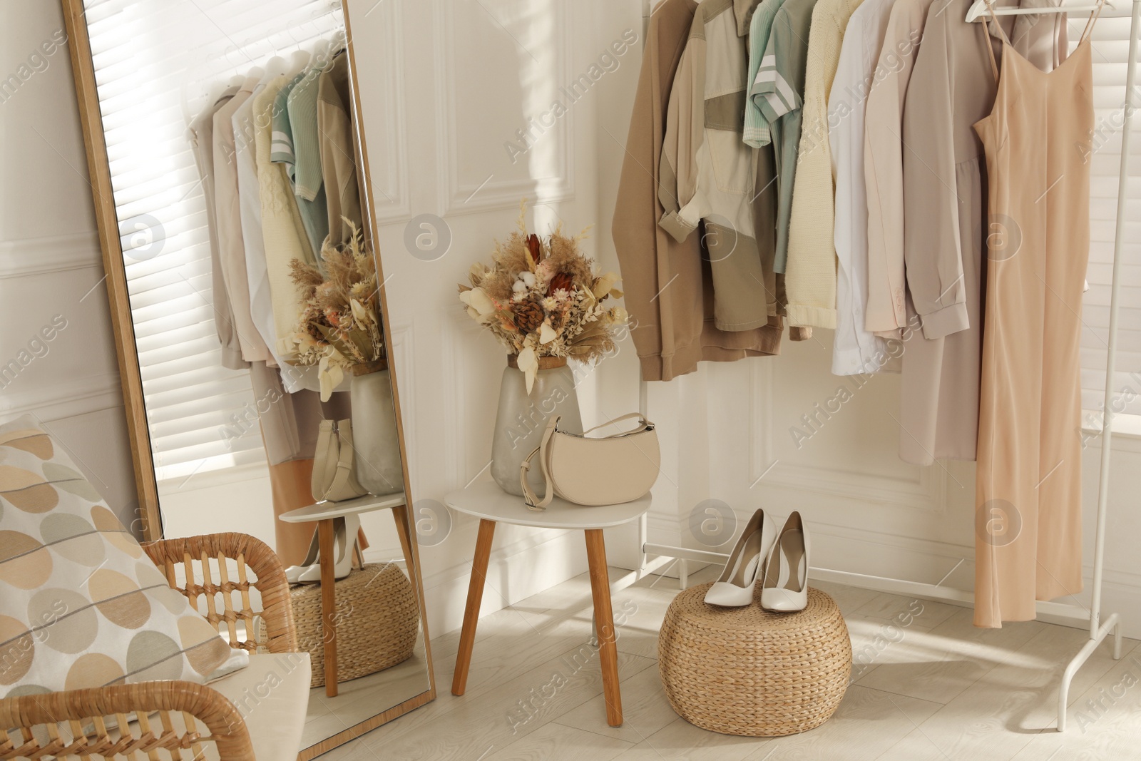 Photo of Modern dressing room interior with stylish clothes, shoes and beautiful dry flowers