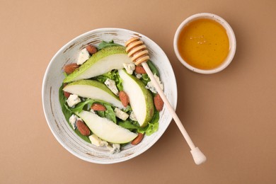 Photo of Delicious pear salad in bowl, honey and dipper on beige background, top view