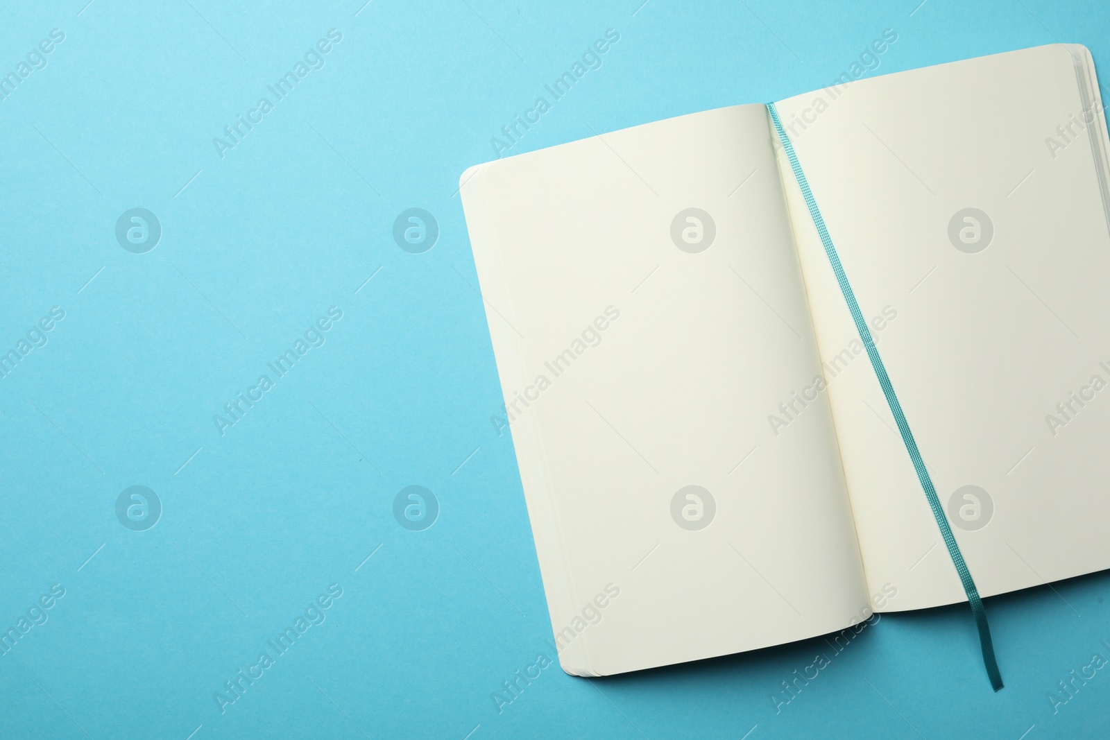 Photo of Stylish open notebook with blank sheets on light blue background, top view. Space for text