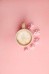 Photo of Cup of coffee and meringues on pink background, top view