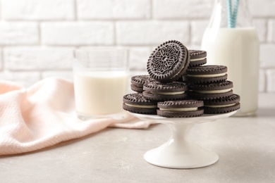 Photo of Cake stand with chocolate sandwich cookies on table against brick wall. Space for text