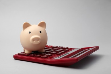 Calculator and piggy bank on grey background