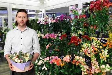 Image of Florist holding basket with flowers in shop 