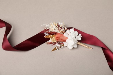 Stylish boutonniere and red ribbon on light grey background, top view