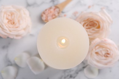 Photo of Spa composition with burning candle, flowers and sea salt on white marble table, top view