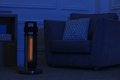 Electric infrared heater in dark living room at night