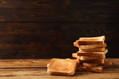 Photo of Slices of tasty toasted bread on wooden table, space for text