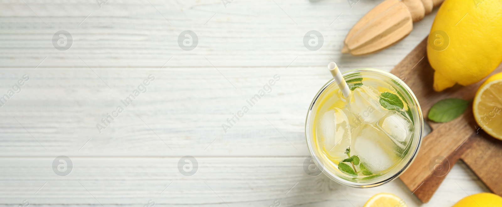 Image of Cool freshly made lemonade, reamer and fruits on white wooden table, flat lay with space for text. Banner design