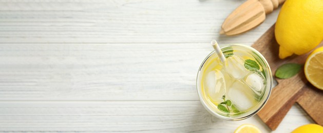 Image of Cool freshly made lemonade, reamer and fruits on white wooden table, flat lay with space for text. Banner design