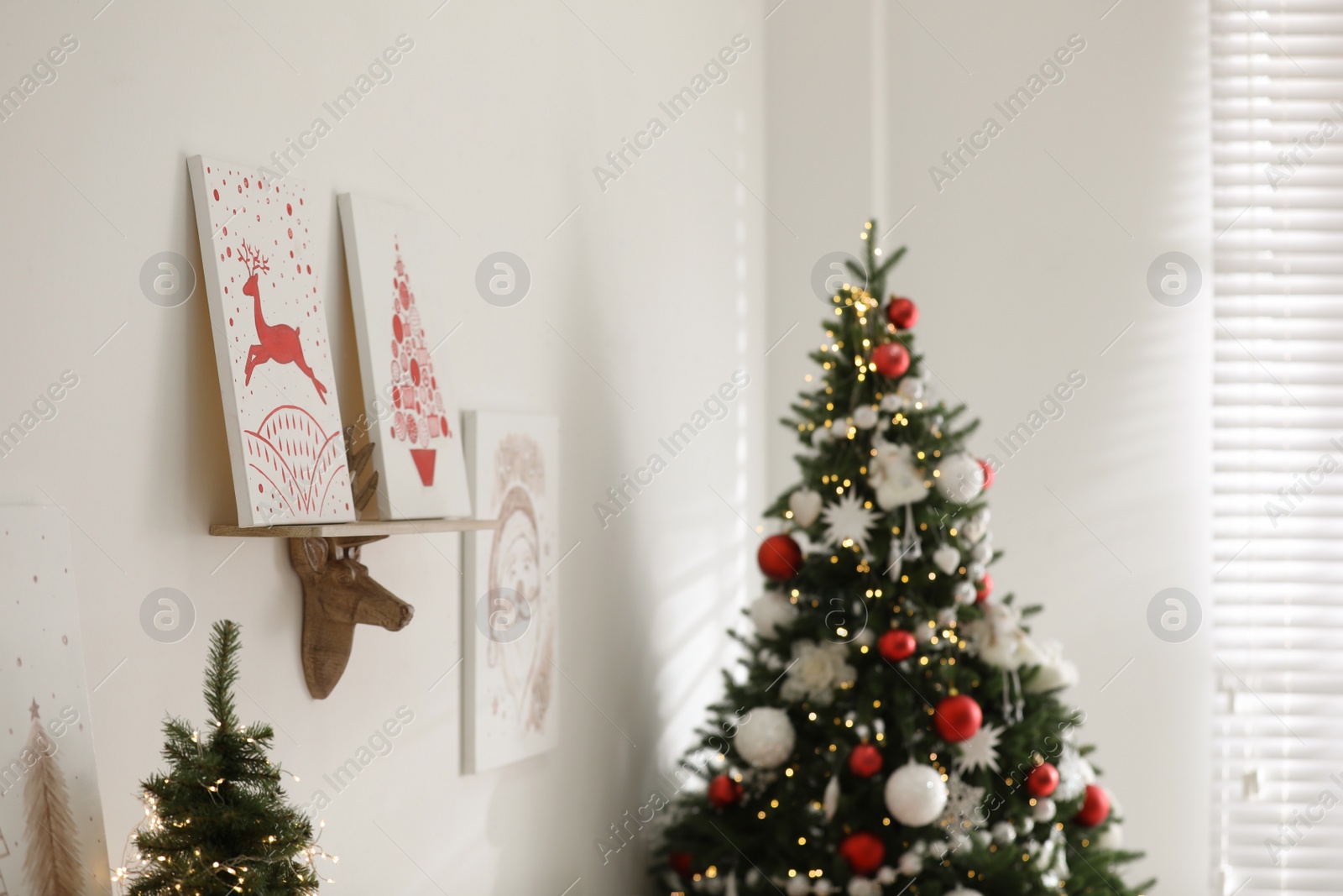 Photo of Beautiful Christmas pictures on white wall indoors. Interior design