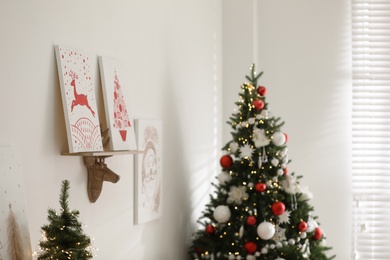 Beautiful Christmas pictures on white wall indoors. Interior design