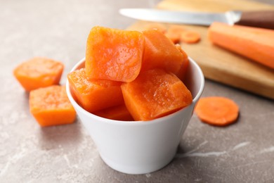 Photo of Bowl of frozen carrot puree cubes and ingredient on marble table, closeup
