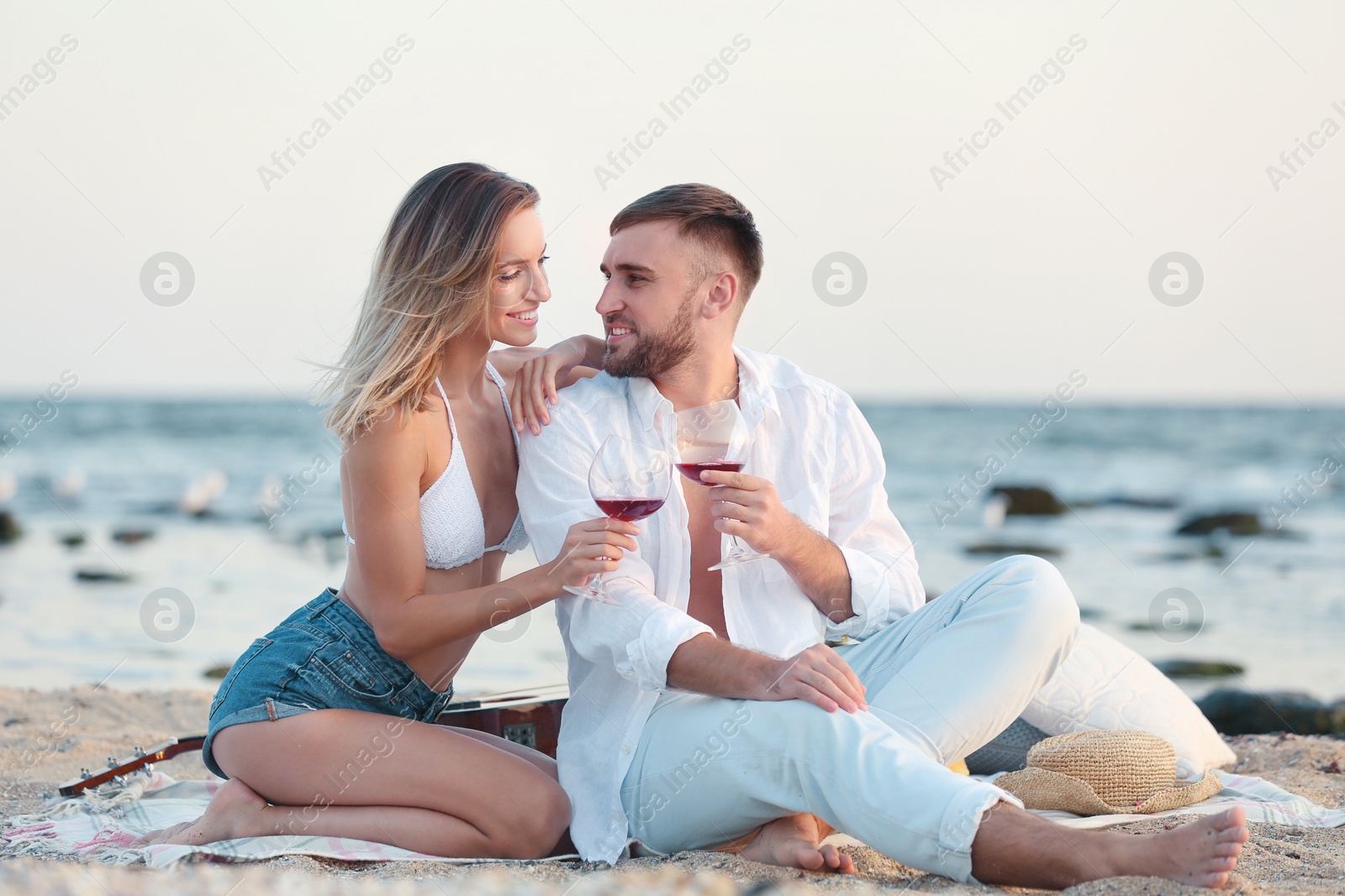 Photo of Young couple with glasses of wine on beach