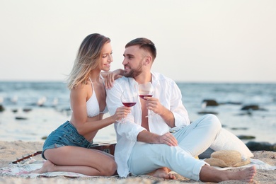 Young couple with glasses of wine on beach