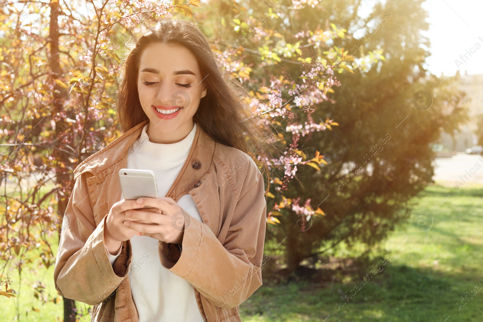 Photo of Young woman using phone outdoors on sunny day