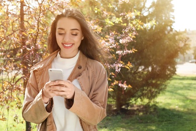 Photo of Young woman using phone outdoors on sunny day