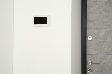 Modern video intercom on white wall near door