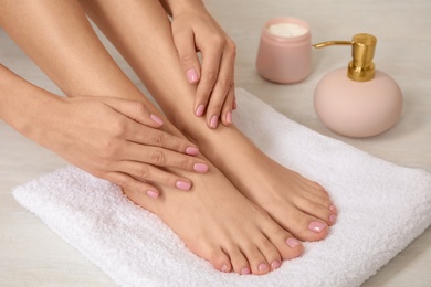 Photo of Woman touching her smooth feet on white towel, closeup. Spa treatment
