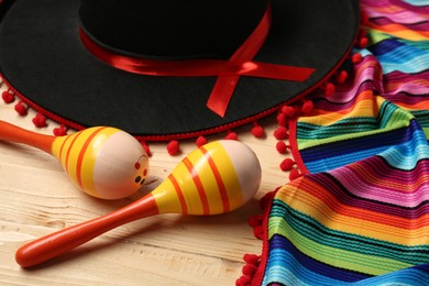 Mexican sombrero hat, maracas and colorful poncho on wooden background